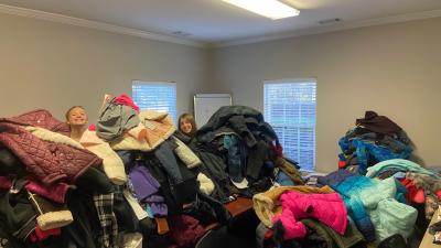 volunteers behind pile of donated coats