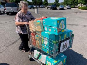 Mable Reynolds pushes cart of diapers for UWSC Mom & Baby Care Drive