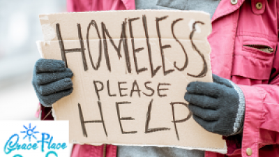 lady in coat and gloves holding homeless sign